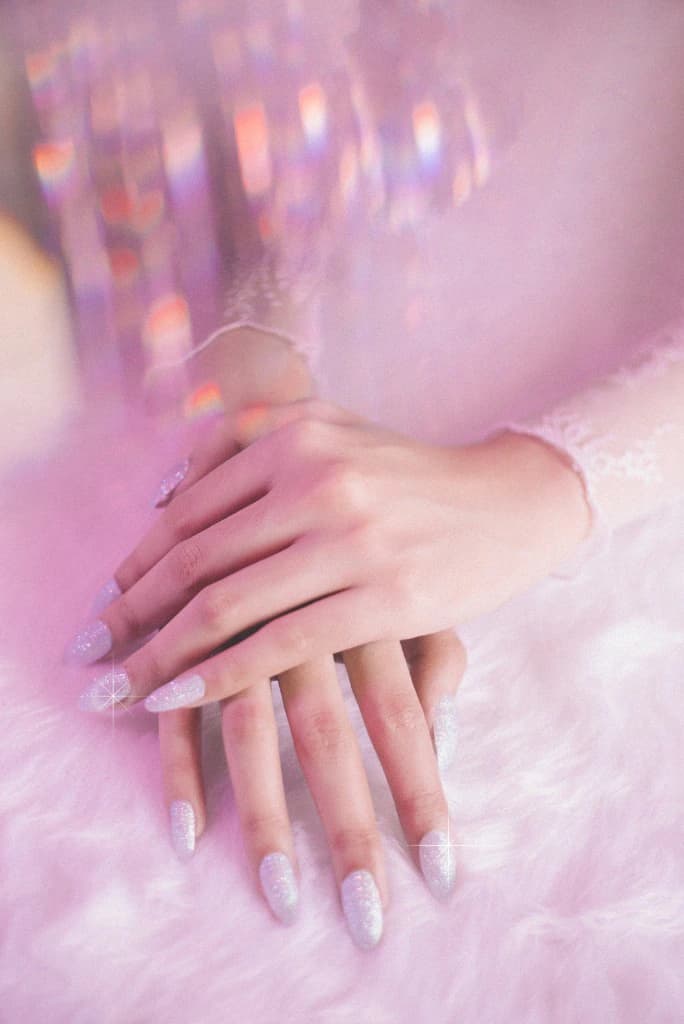 Glitter manicured hands resting on soft white fur